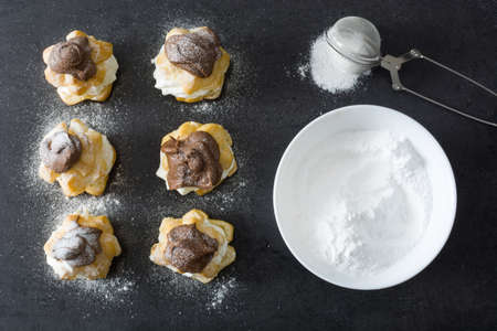 Fresh profiteroles with cream and chocolate frosting on slate
