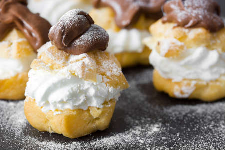 Fresh profiteroles with cream and chocolate frosting on slateの写真素材