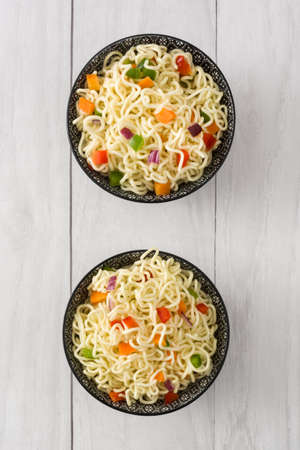 Asian noodles and vegetables on a white wood