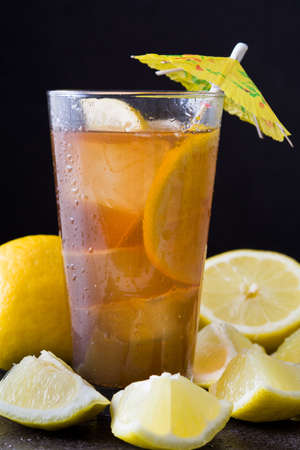 Ice tea with lemon. Black stone background