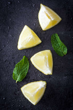 Pieces of lemon and peppermint on black stone backgroundの写真素材
