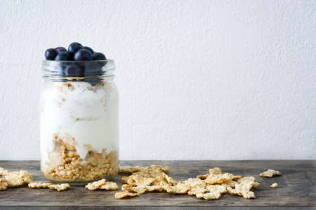 Yogurt with fresh blueberries on wood