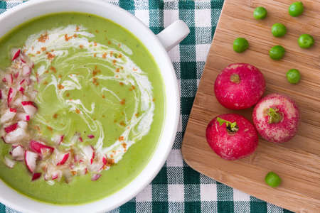 Pea cream with radishes on green tableclothの写真素材