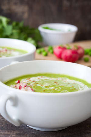 Pea cream with radishes on a rustic wooden backgroundの写真素材
