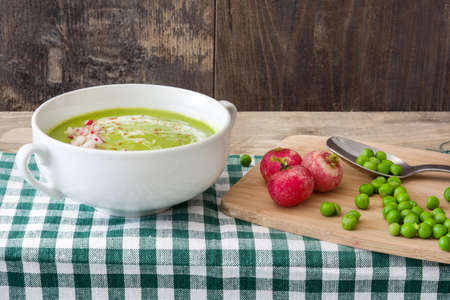 Peas cream with radishes on woodの写真素材
