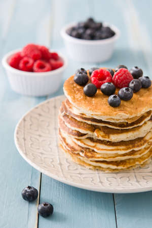 Pancakes with blueberries and raspberry on blue wood backgroundの写真素材
