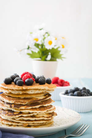 Pancakes with blueberries and raspberry on blue wood backgroundの写真素材