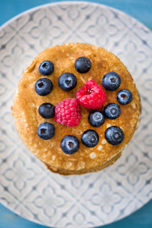 Pancakes with blueberries and raspberry on blue wood backgroundの写真素材