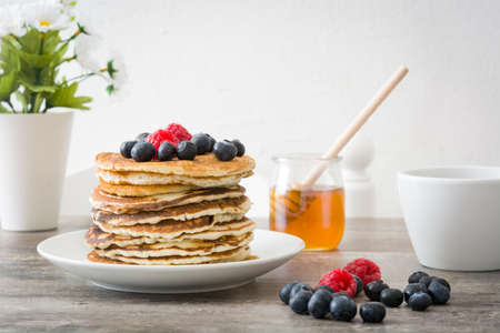 American pancakes with raspberries and blueberries on rustic woodの写真素材