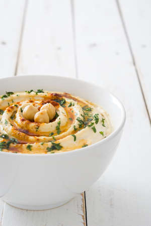 Hummus in white bowl on white woodの写真素材