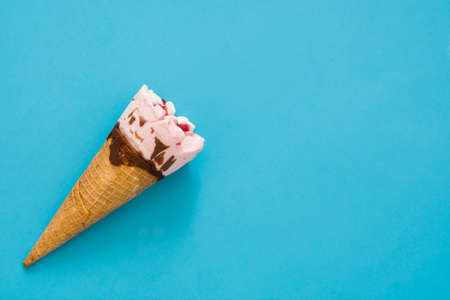 Strawberry ice cream cone on blue background