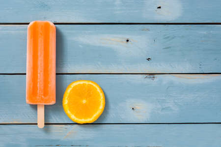 Orange popsicles on blue wooden backgroundの写真素材