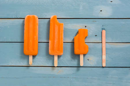Orange popsicles on blue woodenの写真素材