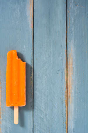 Orange popsicles on blue woodenの写真素材