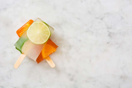 Orange and lime popsicle popsicle on marble tableの写真素材