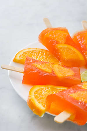 Homemade orange popsicles on marble tableの写真素材