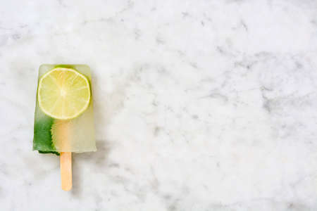 Lime popsicles on white wooden tableの写真素材