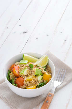 Quinoa salad with zucchini, tomatoes and spinach on white wooden tableの写真素材