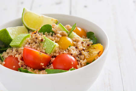 Quinoa salad with zucchini, tomatoes and spinach on white wooden tableの写真素材