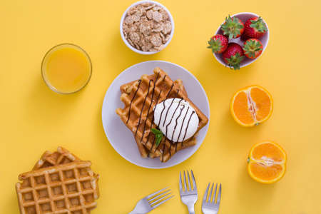 Waffles with chocolate sauce, ice cream and mint on yellow backgroundの写真素材