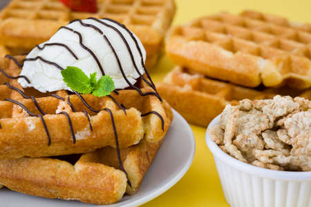Waffles with chocolate sauce, ice cream and mint on yellow backgroundの写真素材