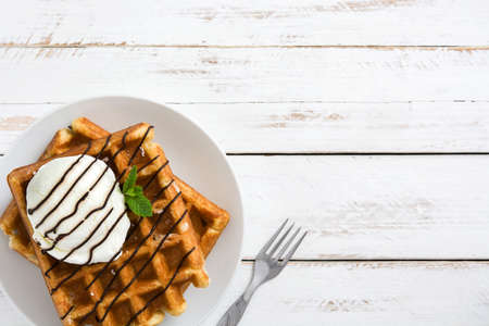 Waffles with ice cream on a white wooden tableの写真素材