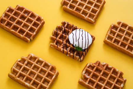 Waffles with ice cream on yellow background