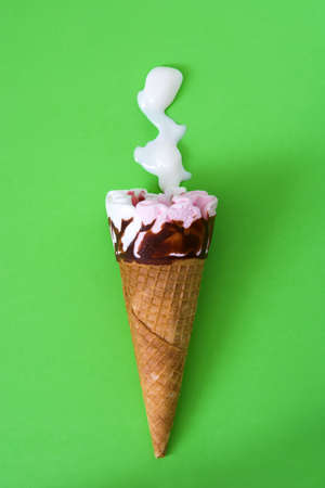 Strawberry ice cream cone on green backgroundの写真素材