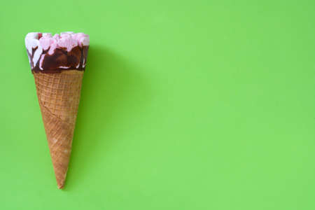 Strawberry ice cream cone on green backgroundの写真素材