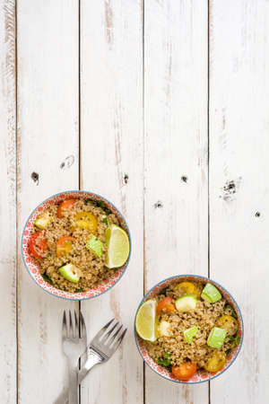 Quinoa with tomatoes, zucchini and lime on white wooden tableの写真素材