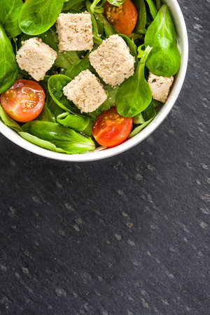 Vegan tofu salad with tomatoes and lamb's lettuce on slateの写真素材