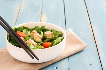 Vegan tofu salad with tomatoes and lamb's lettuce on blue woodの写真素材