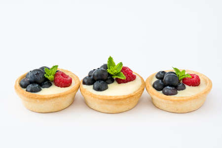 Delicious tartlets with raspberries and blueberries isolated on white backgroundの写真素材