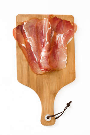 Thin slices of spanish serrano ham on a table isolated on white backgroundの写真素材