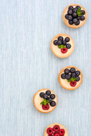 Delicious tartlets with raspberries and blueberries on blue backgroundの写真素材