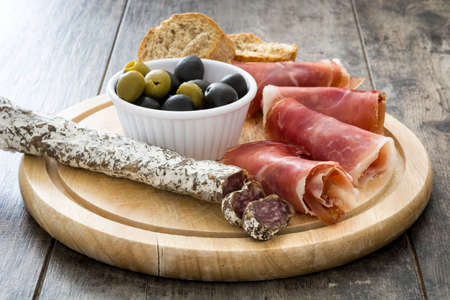 Spanish serrano ham, olives and sausage on a rustic wooden table