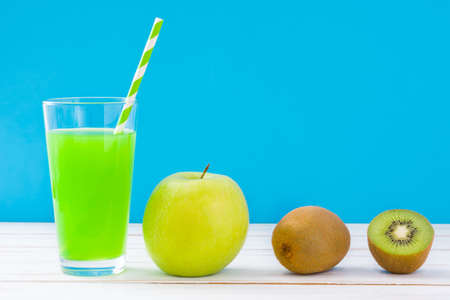 Green smoothie with apple and kiwi on a white wooden table and blue backgroundの写真素材