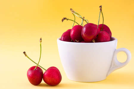 Cherries in a cup on yellow backgroundの写真素材