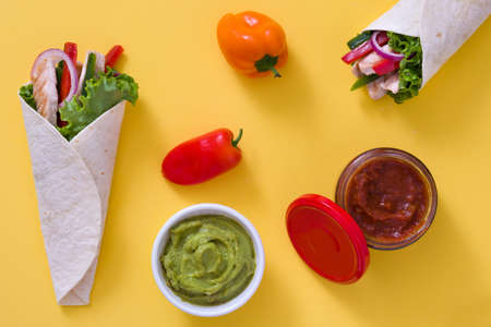 Mexican chicken fajita with peppers lettuce and onion on yellow background