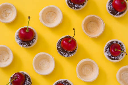 Delicious chocolate tartlets With One cherry, chocolate and coconut on yellow backgroundの写真素材