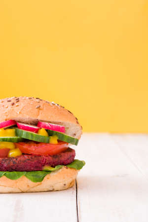 Veggie burger on white wooden beet and yellow backgroundの写真素材