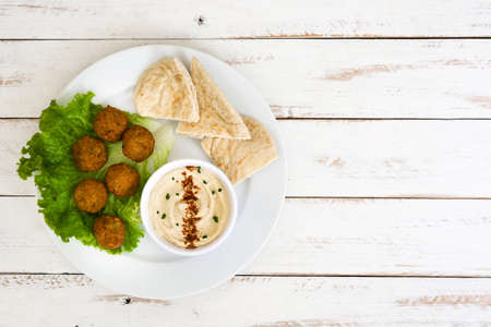 Vegetarian falafels in bowl and vegetables on white woodの写真素材
