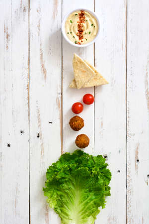 Vegetarian falafels and vegetables on a white wooden background