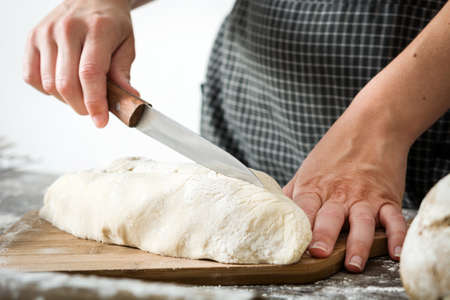 Woman cutting bread dough on wood table