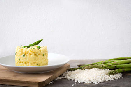 Risotto with asparagus, parsley and peas on a rustic wooden tableの写真素材