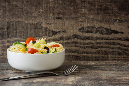 Pasta salad in bowl on rustic wooden table
