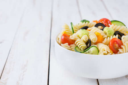 Pasta salad in bowl on white wooden tableの写真素材