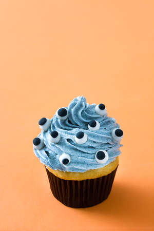 Halloween cupcake with eyes on orange backgroundの写真素材