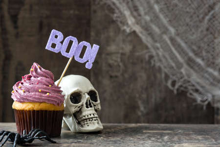 Halloween cupcake and skull on rustic wooden backgroundの写真素材