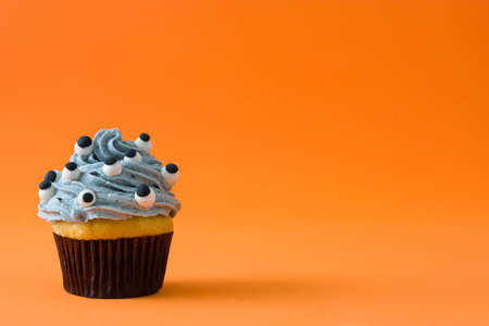 Halloween cupcake with eyes on orange backgroundの写真素材